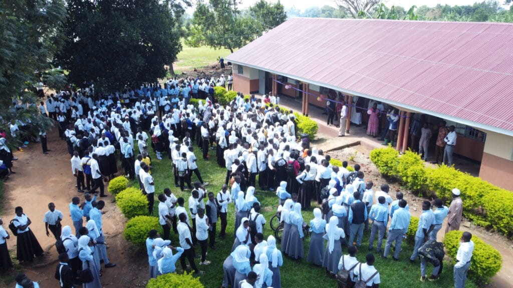 Happy Ugandan students standing outside their newly completed, modern school building.
