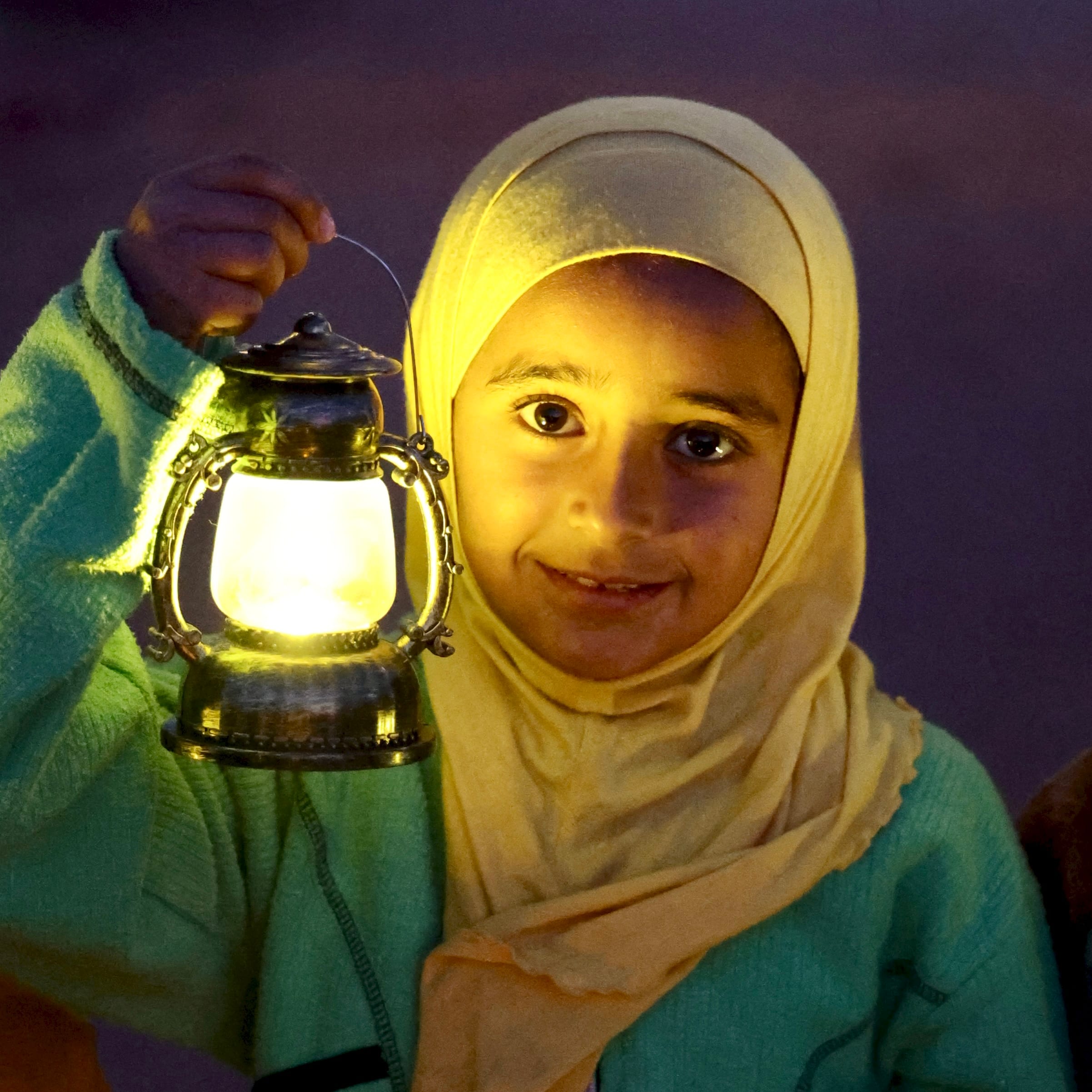 "A young girl holding a glowing lantern at night"