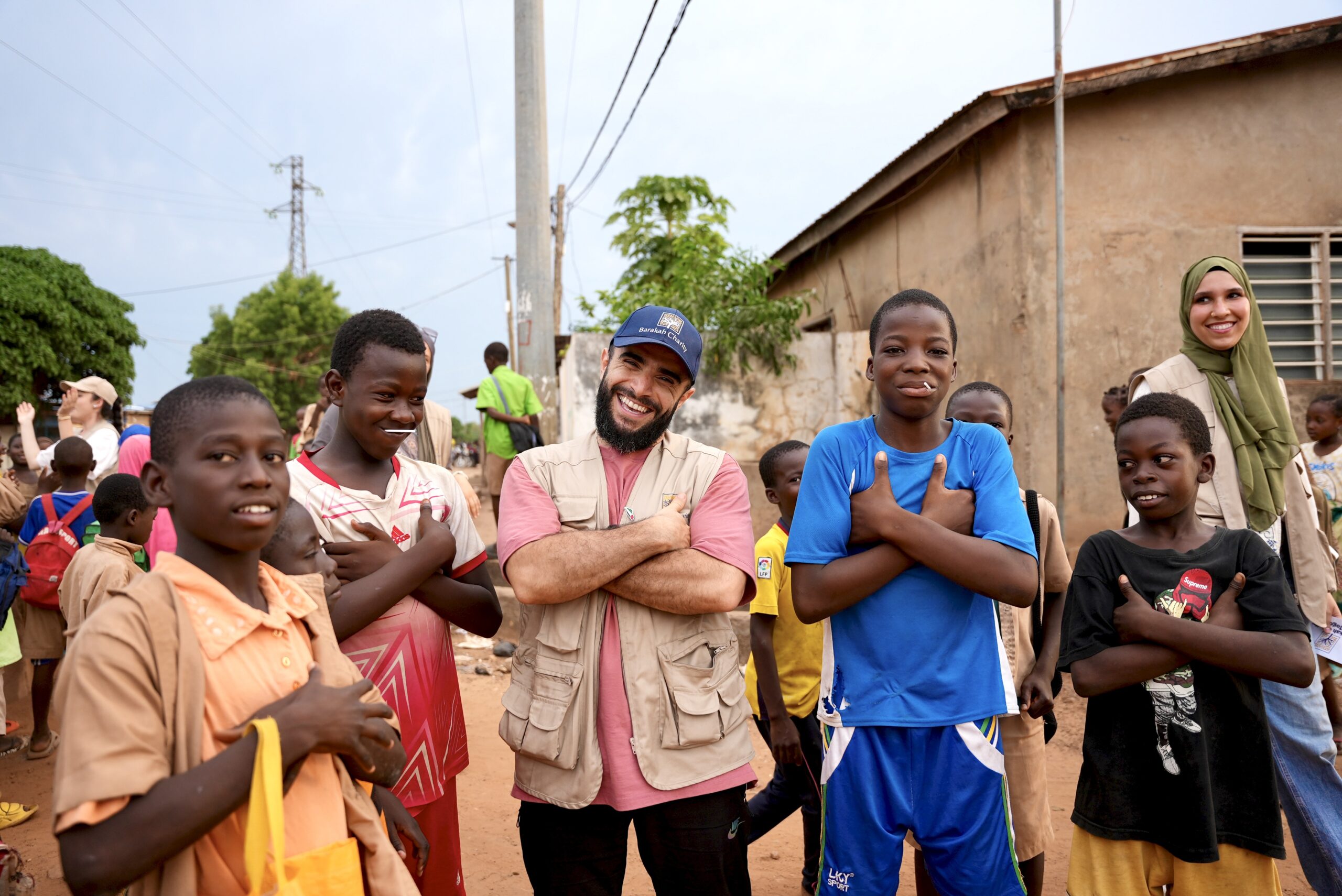 Barakah Charity volunteers posing happily with local children during a field aid mission.